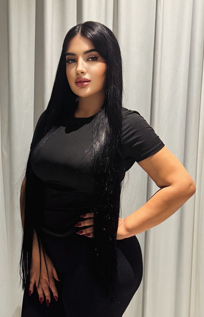 Brunette massage therapist against a backdrop of satin white curtains